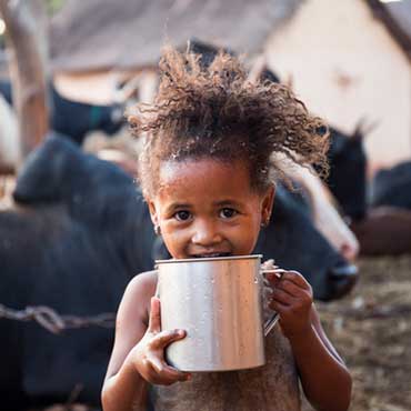 Female toddler drinking water from large mug